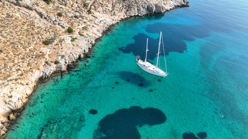Ghid Mykonos — Golful Ornos cu apă turcoaz și barcă cu pânze