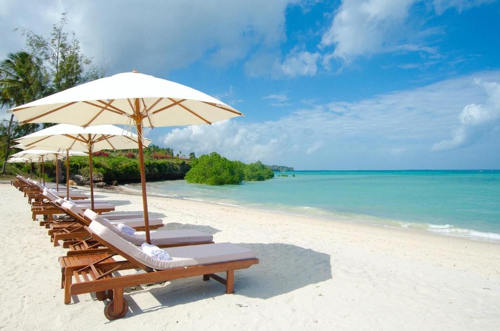 Vacanță exotică în Zanzibar — plajă cu nisip alb, șezlonguri și apă turcoaz în Oceanul Indian.